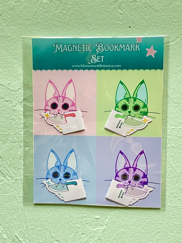 Magnetic knife bookmarks displayed with 4 colored cats holding the knives in their mouth